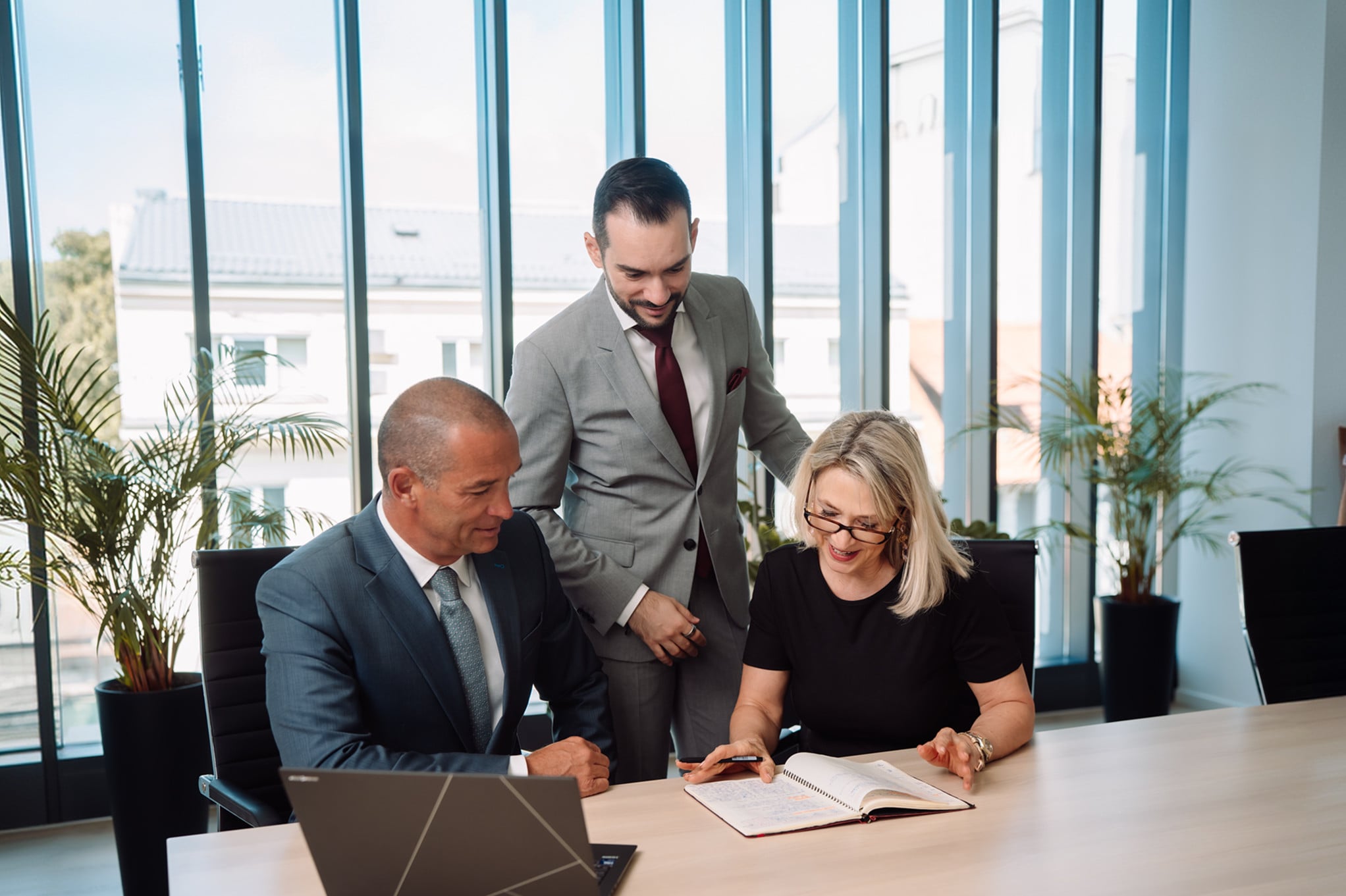 Three advisors reviewing a plan together at a meeting table in a bright office.