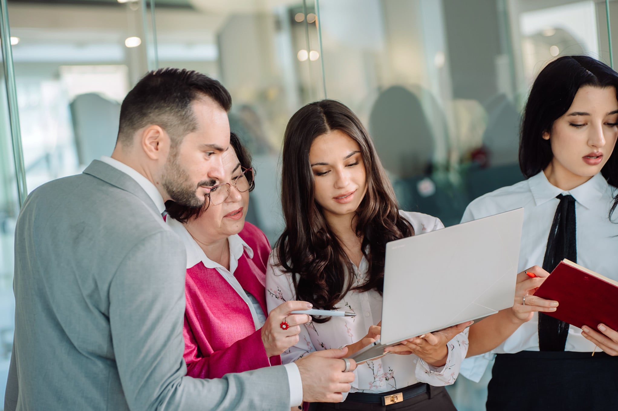 Four advisors standing around a laptop, reviewing a transaction together.
