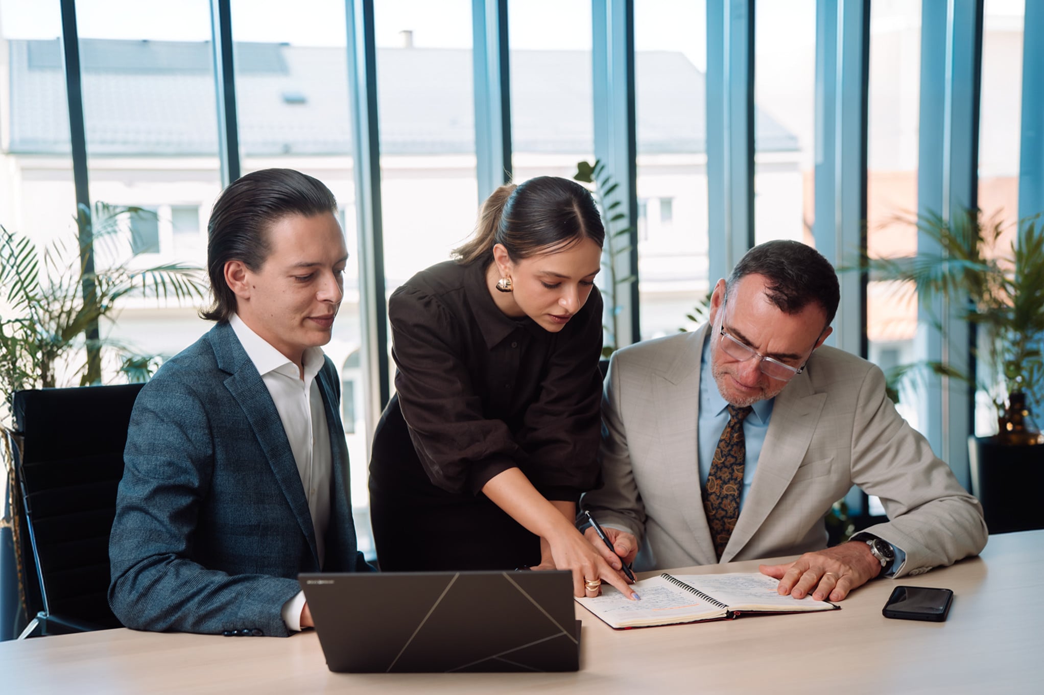 Three advisors from different practices working through documents together at a meeting table.